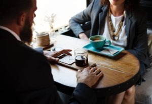 businessman in suit speaking with businesswoman in suit over two cups of coffee