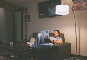 college student sitting on a couch working on his laptop